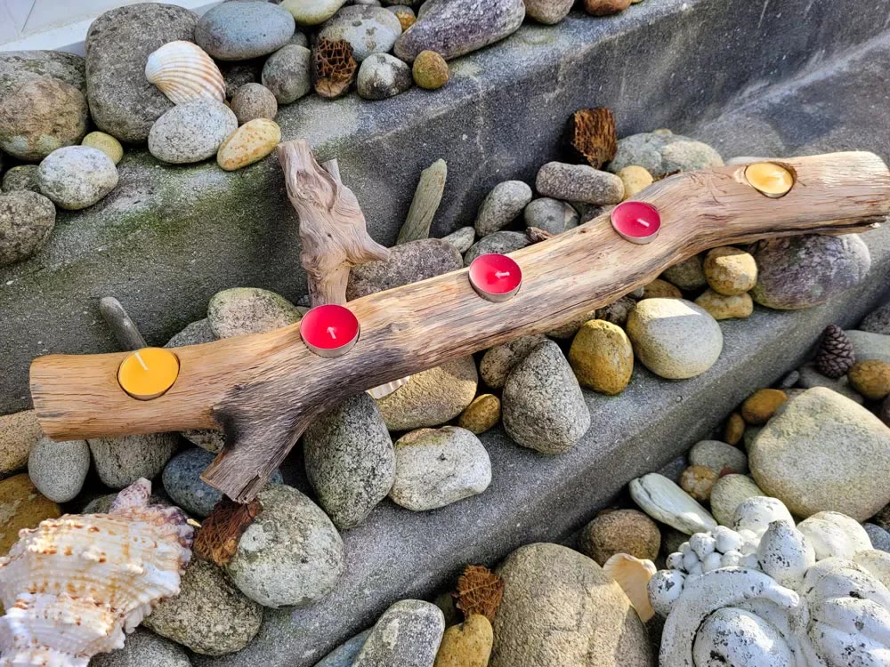 Bougeoir en bois flotté avec bougies chauffe-plat, posé sur des galets