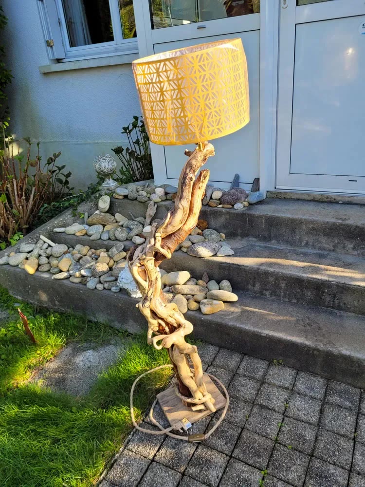 Lampadaire en bois flotté au tronc torsadé avec abat-jour ajouré, devant la maison
